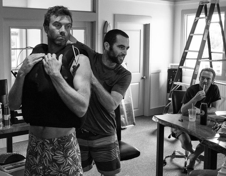 Two surfers looking at a PSI Vest.